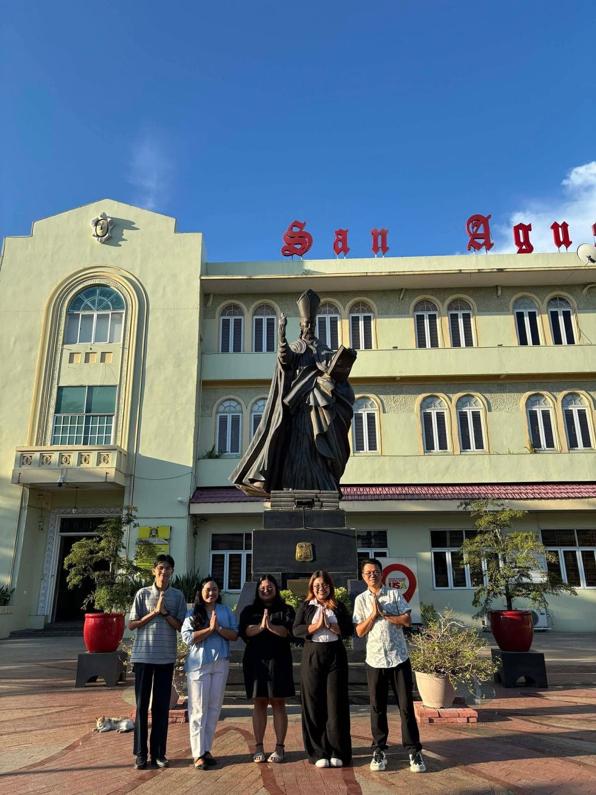 The five St. Joseph's Academy teachers standing before the statue of St. Augustine outside the University of San Agustin